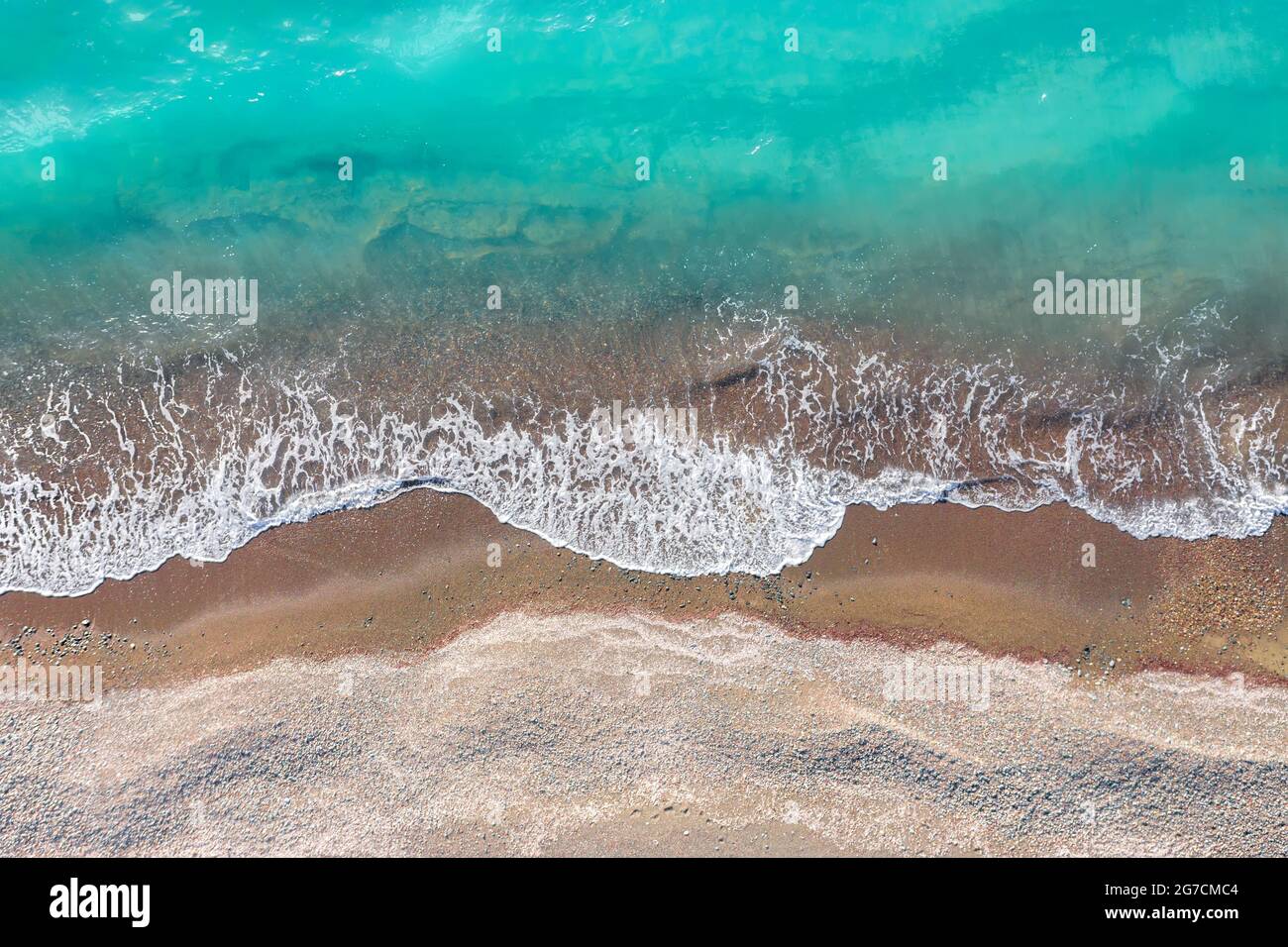 Vagues de mer se brisant sur une rive de sable jaune, vue de dessus directement au-dessus Banque D'Images