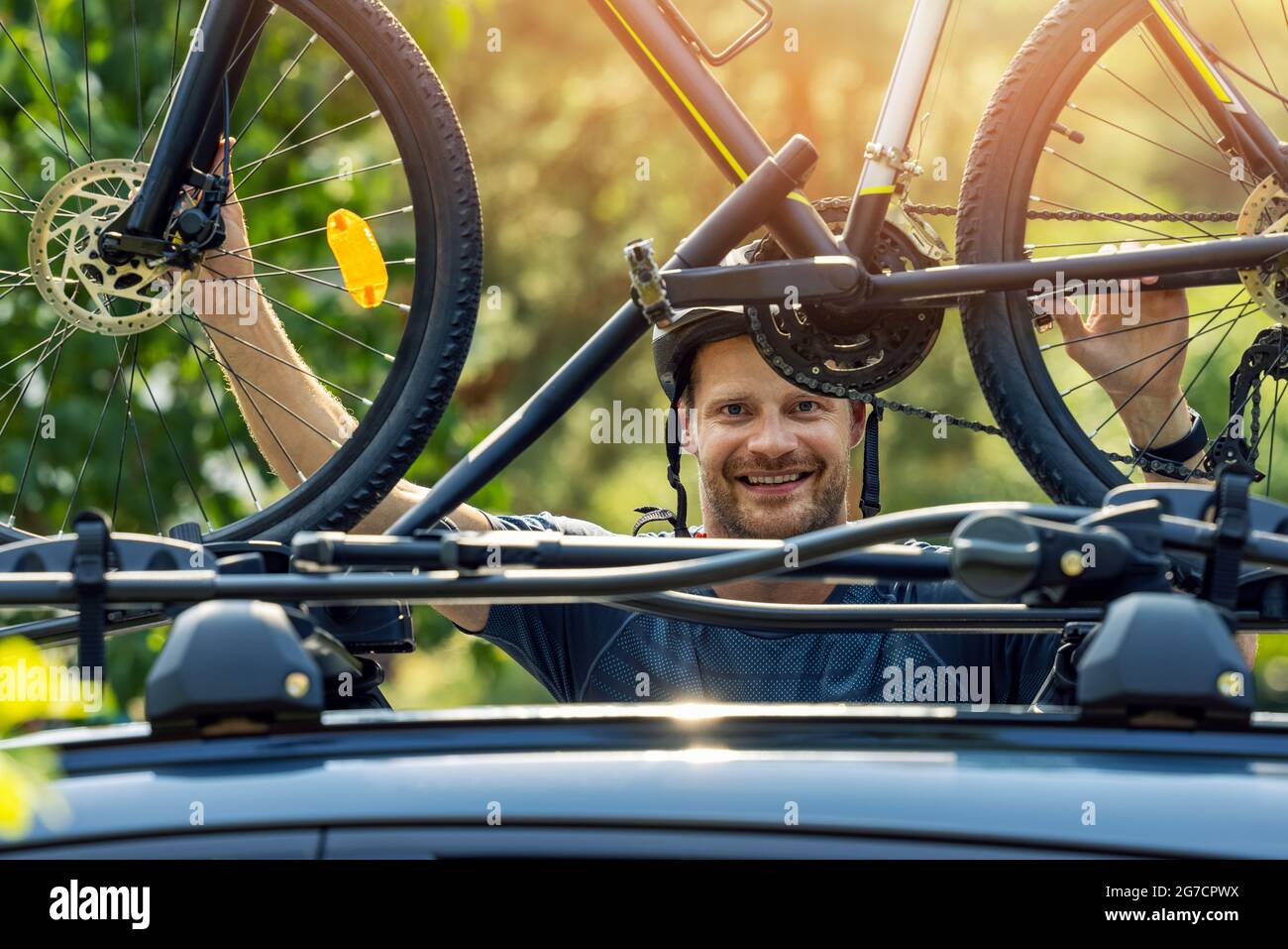 cycliste souriant montant son vélo sur le porte-bagages de toit de voiture Banque D'Images