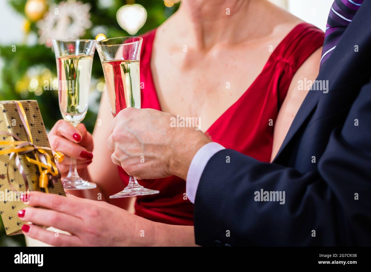 Man and Woman celebrating Christmas Eve avec un verre de vin mousseux Banque D'Images