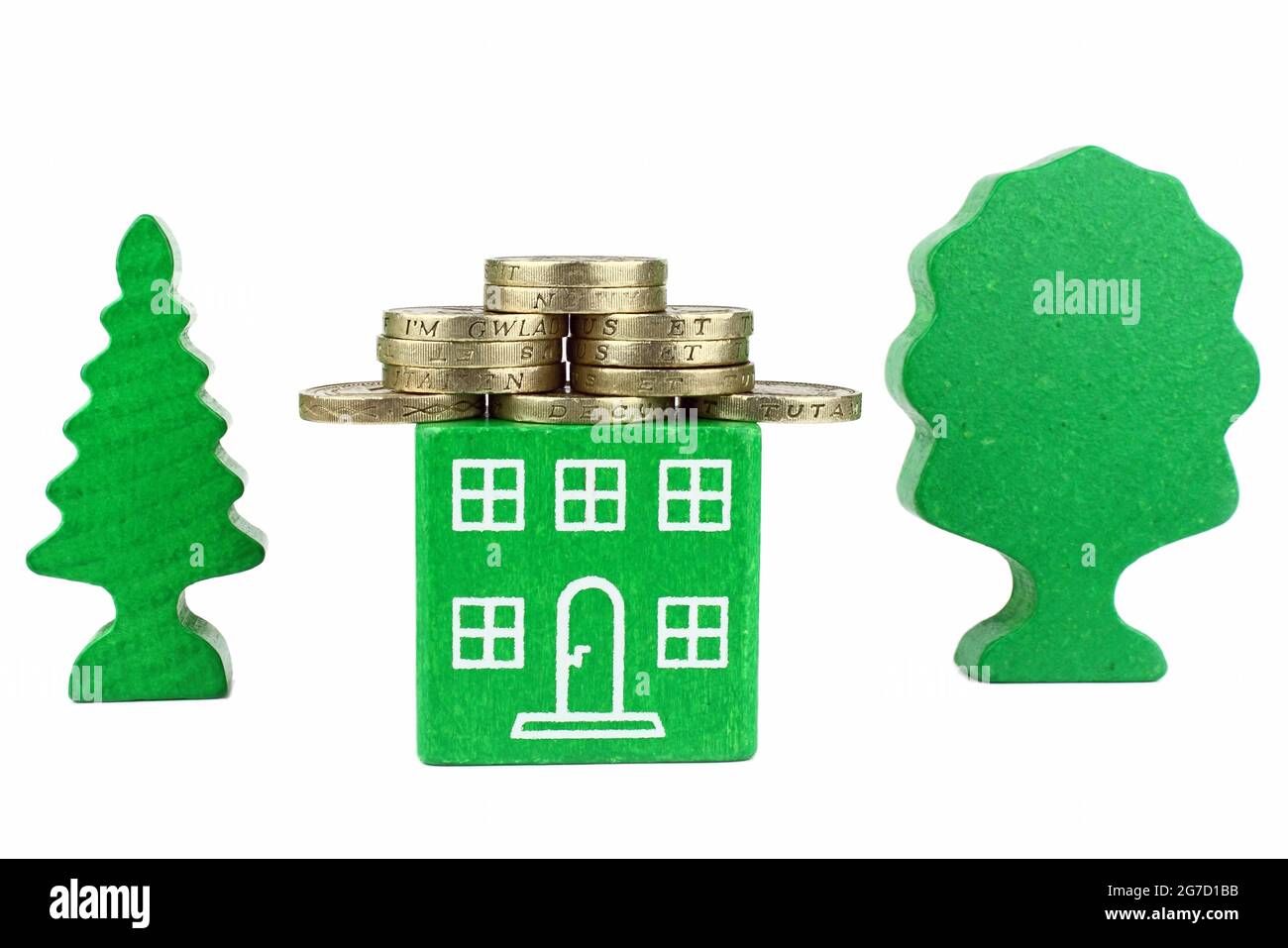 Une maison verte avec des pièces de monnaie pour le toit, représentant des économies à faire avec une maison à économie d'énergie. Banque D'Images