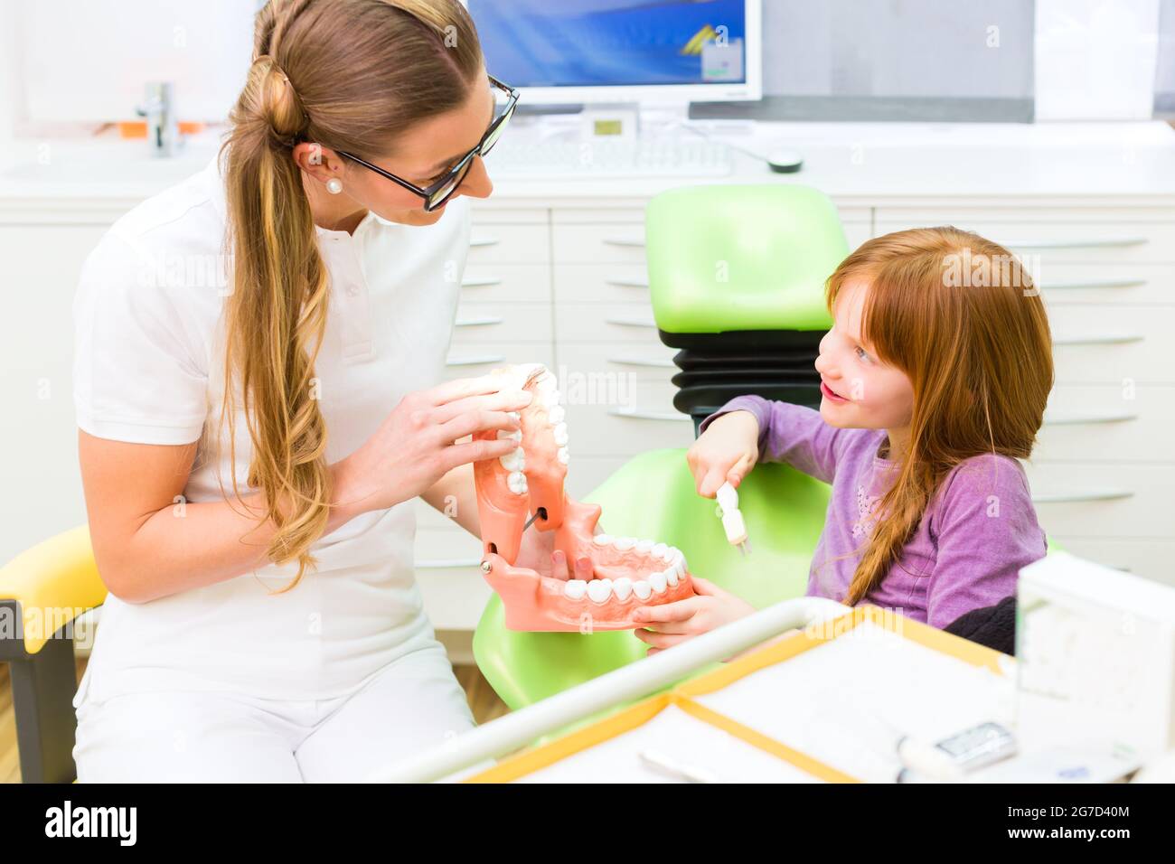 Femme dentiste expliquant girl cleaning dent avec une brosse à dents sur le modèle Banque D'Images