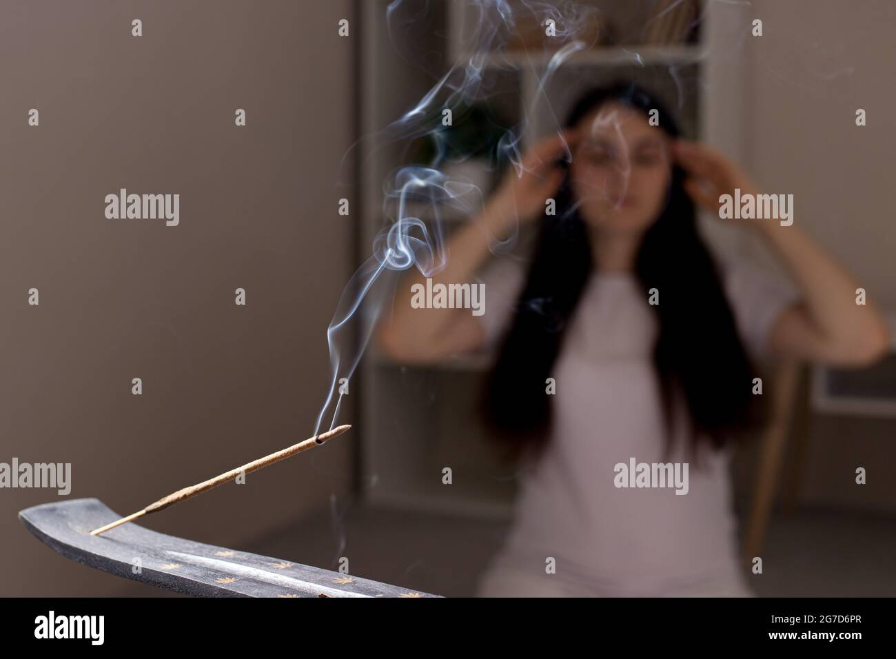 Un bâton indien aromatique est en train de brûler, la femme en arrière-plan est méditant. L'aromathérapie, l'auto-immersion, le pouvoir de la pensée Banque D'Images