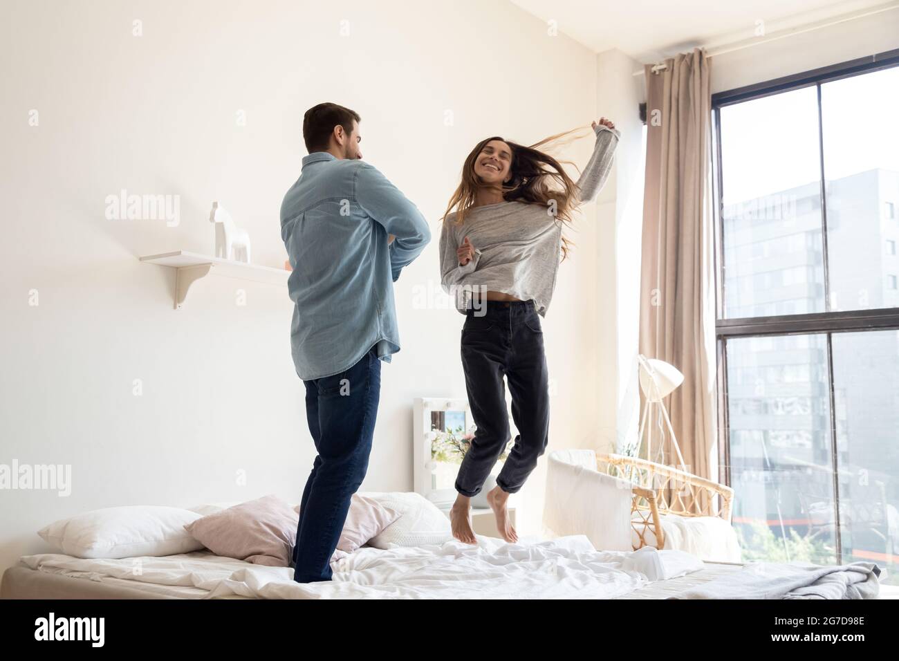 Drôle de couple dansant sauter sur le lit dans la chambre moderne Photo  Stock - Alamy