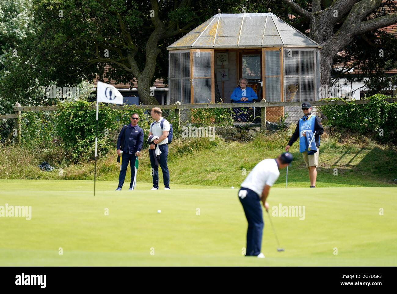 Un résident regarde Justin Rose en Angleterre sur le 4ème green pendant la journée d'entraînement au Royal St George's Golf Club à Sandwich, dans le Kent. Date de la photo: Mardi 13 juillet 2021. Banque D'Images