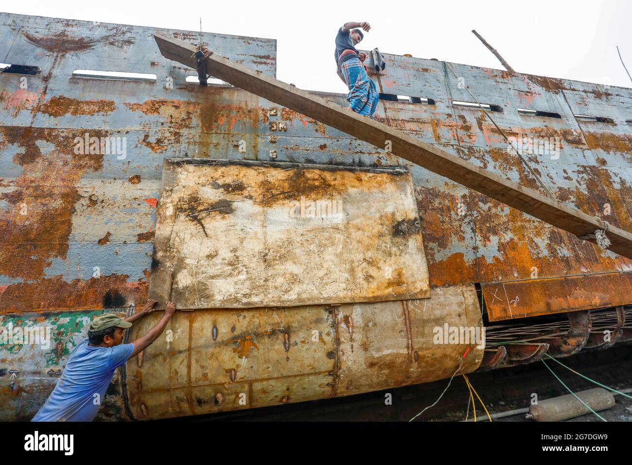 Les travailleurs bangladais réparent un navire dans un chantier naval situé sur la rive du Buriganga, à Keraniganj, près de Dhaka, Bangladesh, juillet 13, 2021. Avec un incrément Banque D'Images