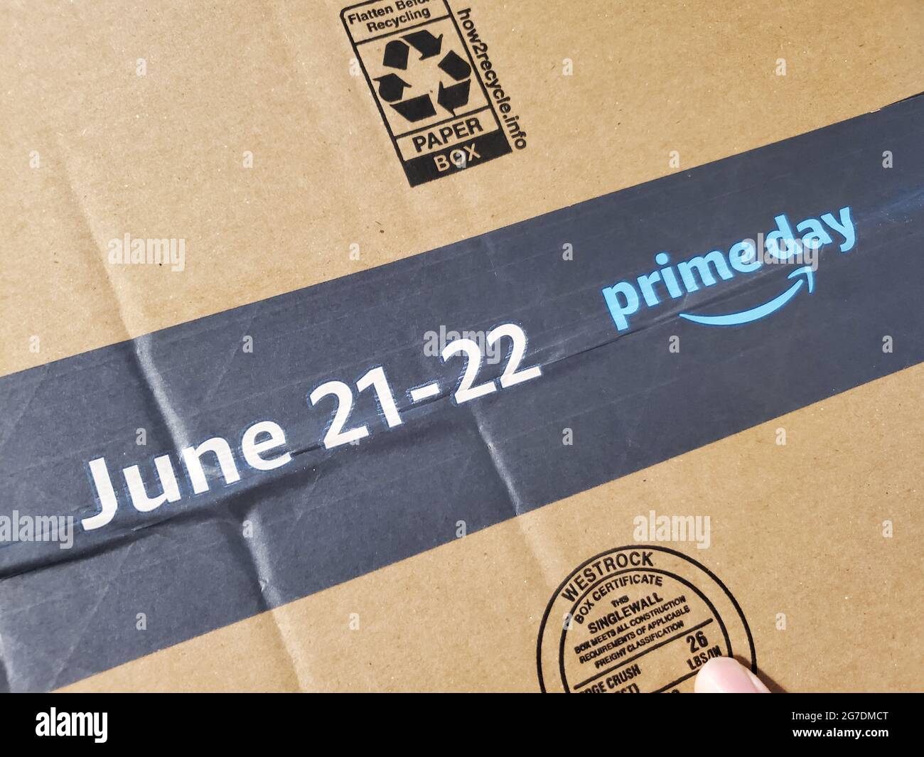 Gros plan du ruban d'emballage sur la boîte d'expédition Amazon, avec le logo pour le premier jour 2021 et les dates du 21-22 juin pour la journée de magasinage populaire, avec une partie de la main visible sur la boîte, Lafayette, Californie, 13 juin 2021. () Banque D'Images