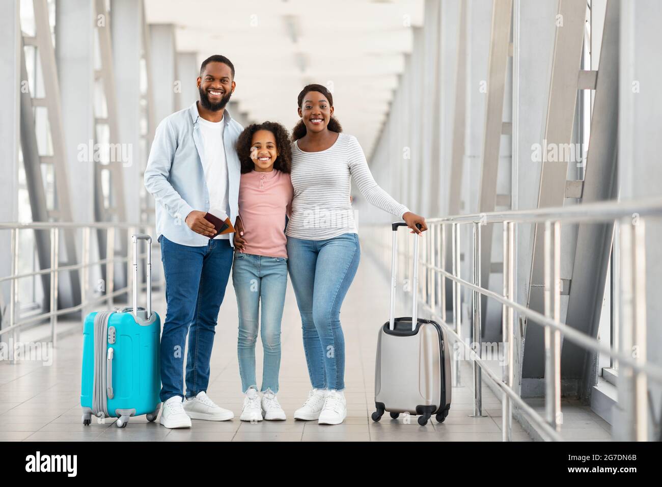 Bonne famille noire excitée voyageant, posant à l'aéroport Banque D'Images