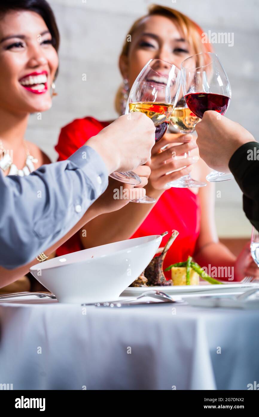 Les amis de l'Asie, deux couples, dîner dans un restaurant de fantaisie manger de la bonne nourriture et de boire du vin Banque D'Images