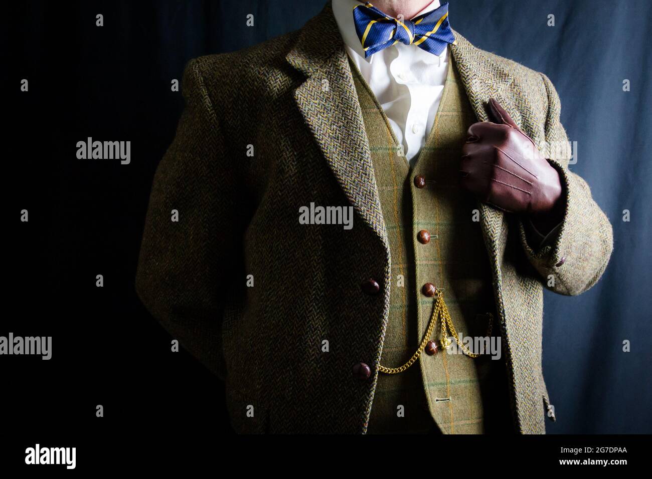 Portrait de l'homme en costume en tweed et gants en cuir debout fièrement sur fond noir. Anglais classique et excentrique gentleman. Mode vintage. Banque D'Images