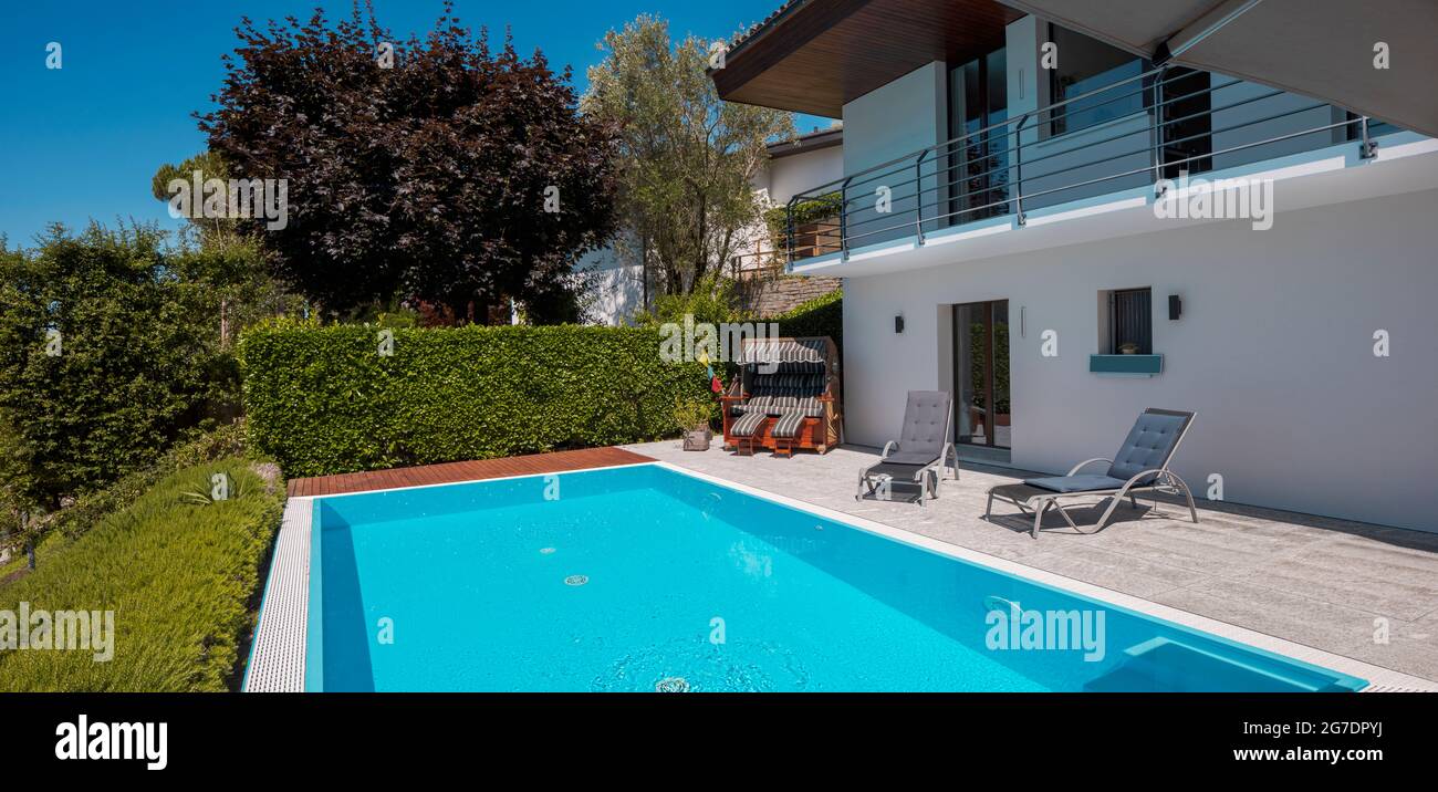 Maison moderne de deux étages avec grande piscine donnant sur les montagnes. Deux chaises longues pour profiter de vos vacances. Personne à l'intérieur Banque D'Images