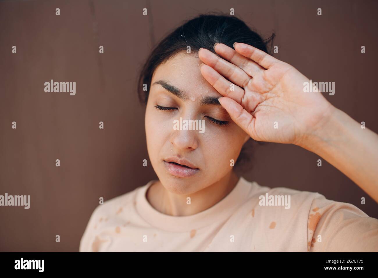 Femme stressée souffrant d'un coup de chaleur rafraîchissant avec de l'eau froide à l'extérieur. Concept de chaleur anormale par temps Banque D'Images