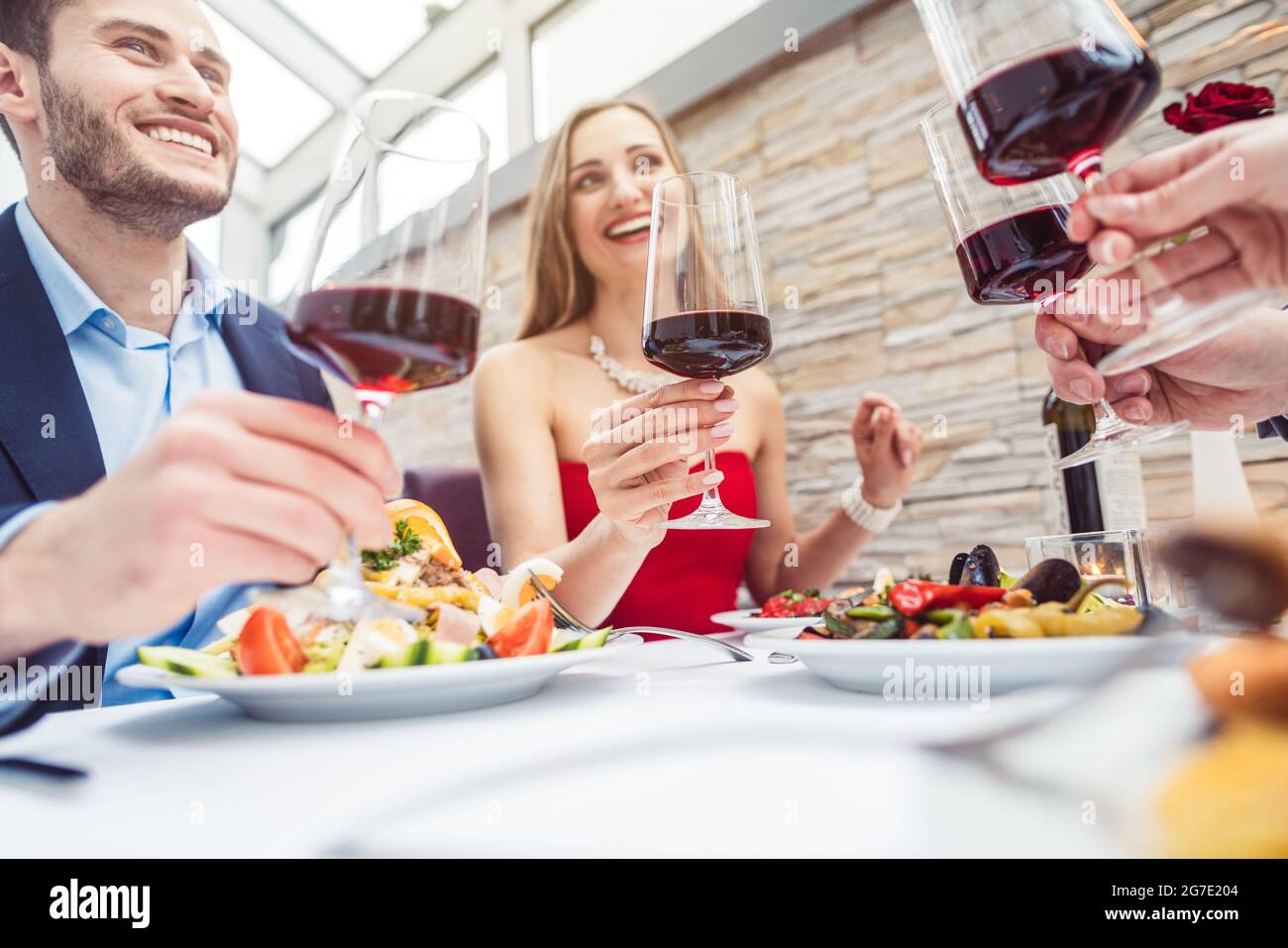 Des amis heureux dans un restaurant chic avec du vin rouge italien Banque D'Images
