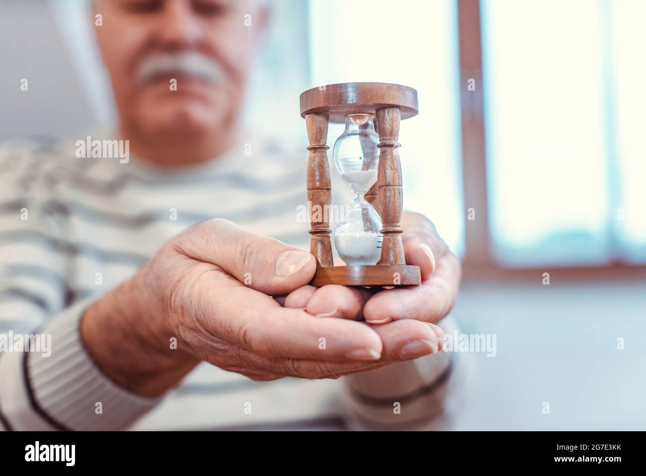 Homme âgé tenant un sablier dans une maison de retraite, symbole pour une durée de vie limitée Banque D'Images