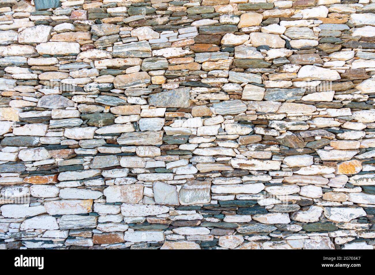 Fond de mur en pierre et en pierre. Texture de surface en pierre vintage et colorée, architecture et construction traditionnelles des îles grecques Banque D'Images