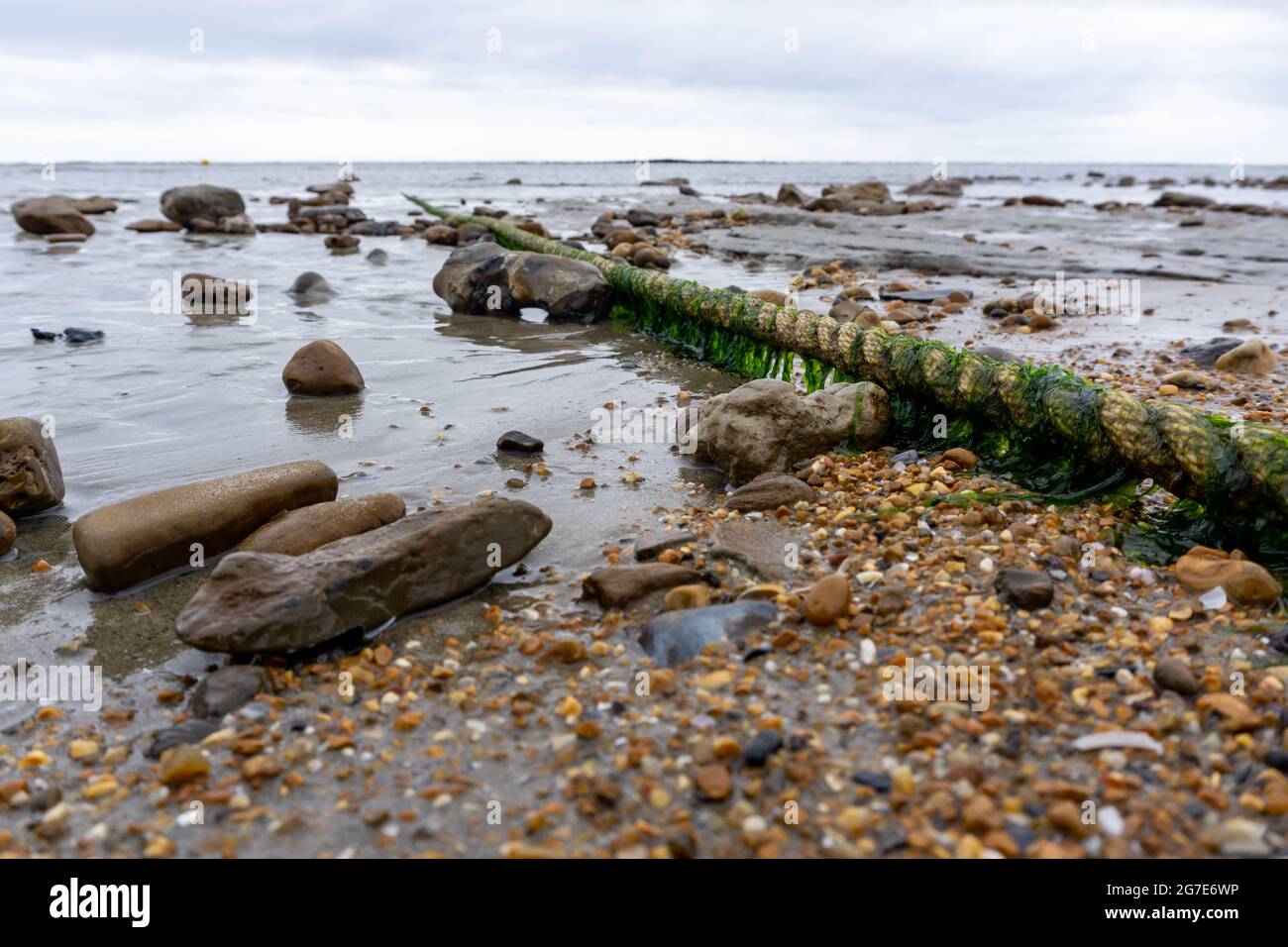 Une vieille corde recouverte d'algues s'étend du rivage à la mer Banque D'Images