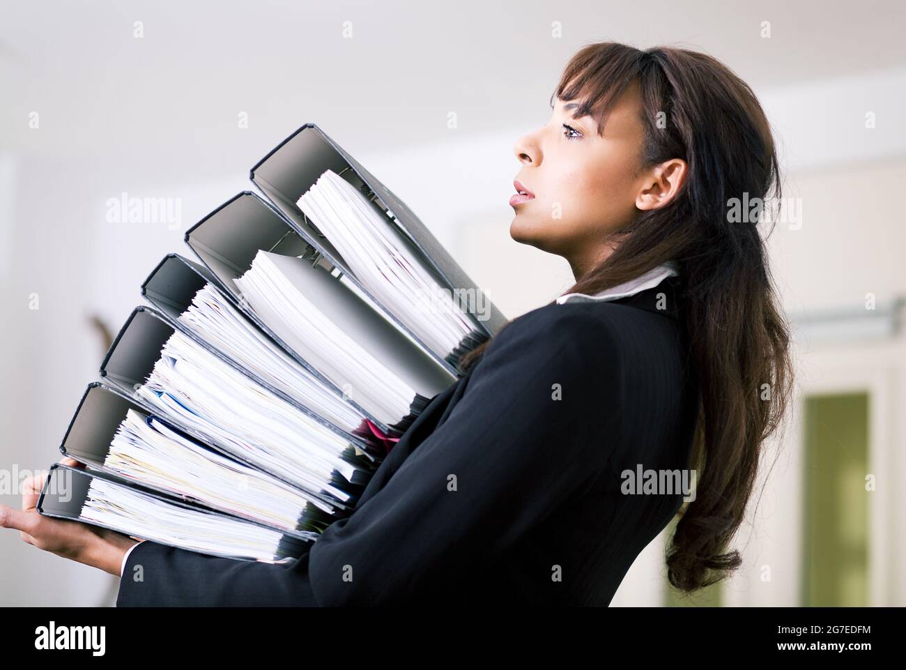Female office worker exerçant son activité sous une pile de dossiers Banque D'Images