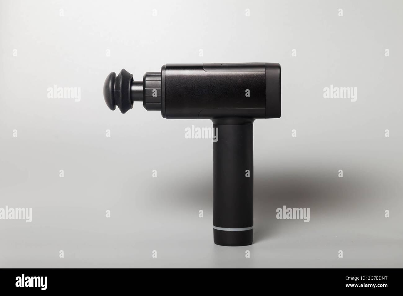 Pistolet de massage thérapeutique professionnel sans fil portable sur fond gris. Masseur à percussion de tissus musculaires profonds pour athlètes, relaxes, rel Banque D'Images