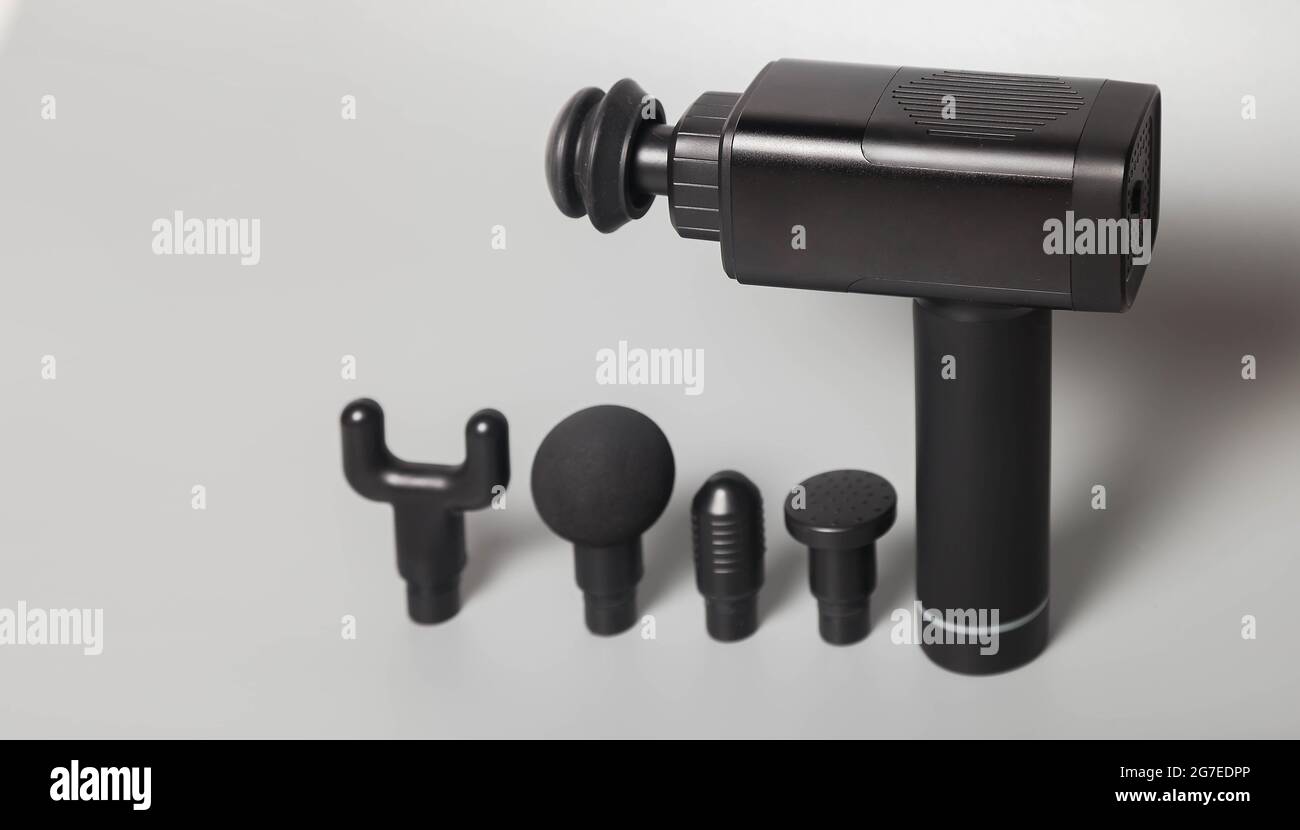 Pistolet de massage thérapeutique professionnel sans fil portable sur fond gris. Masseur à percussion de tissus musculaires profonds pour athlètes, relaxes, rel Banque D'Images