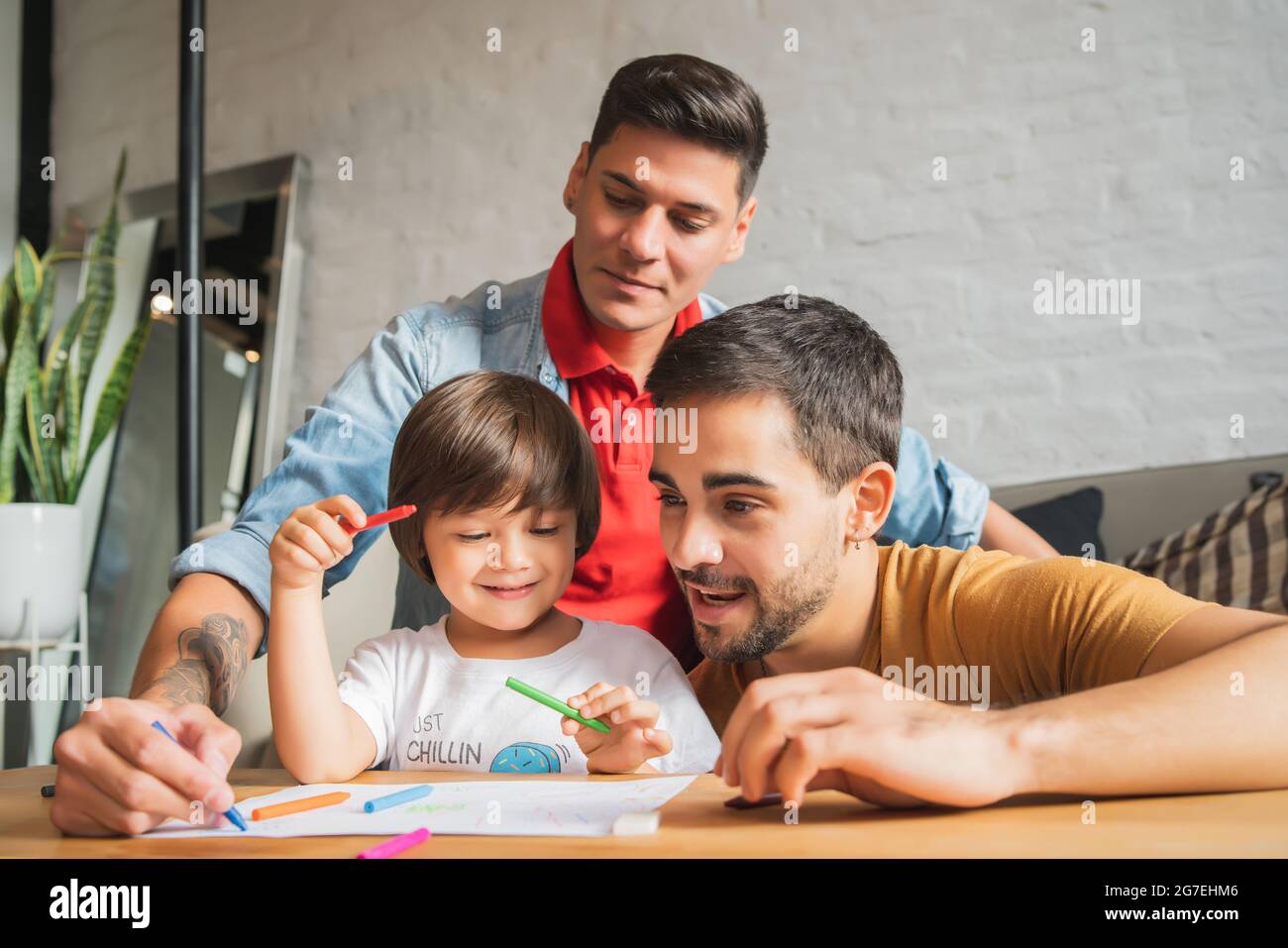 Couple gay et leur fils s'amusant ensemble tout en dessinant à la maison. Banque D'Images