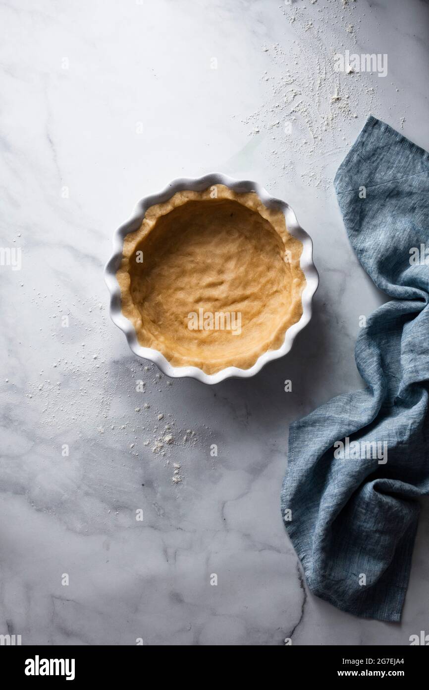 Plat à tarte doublé de pâtisserie avec serviette bleue Banque D'Images