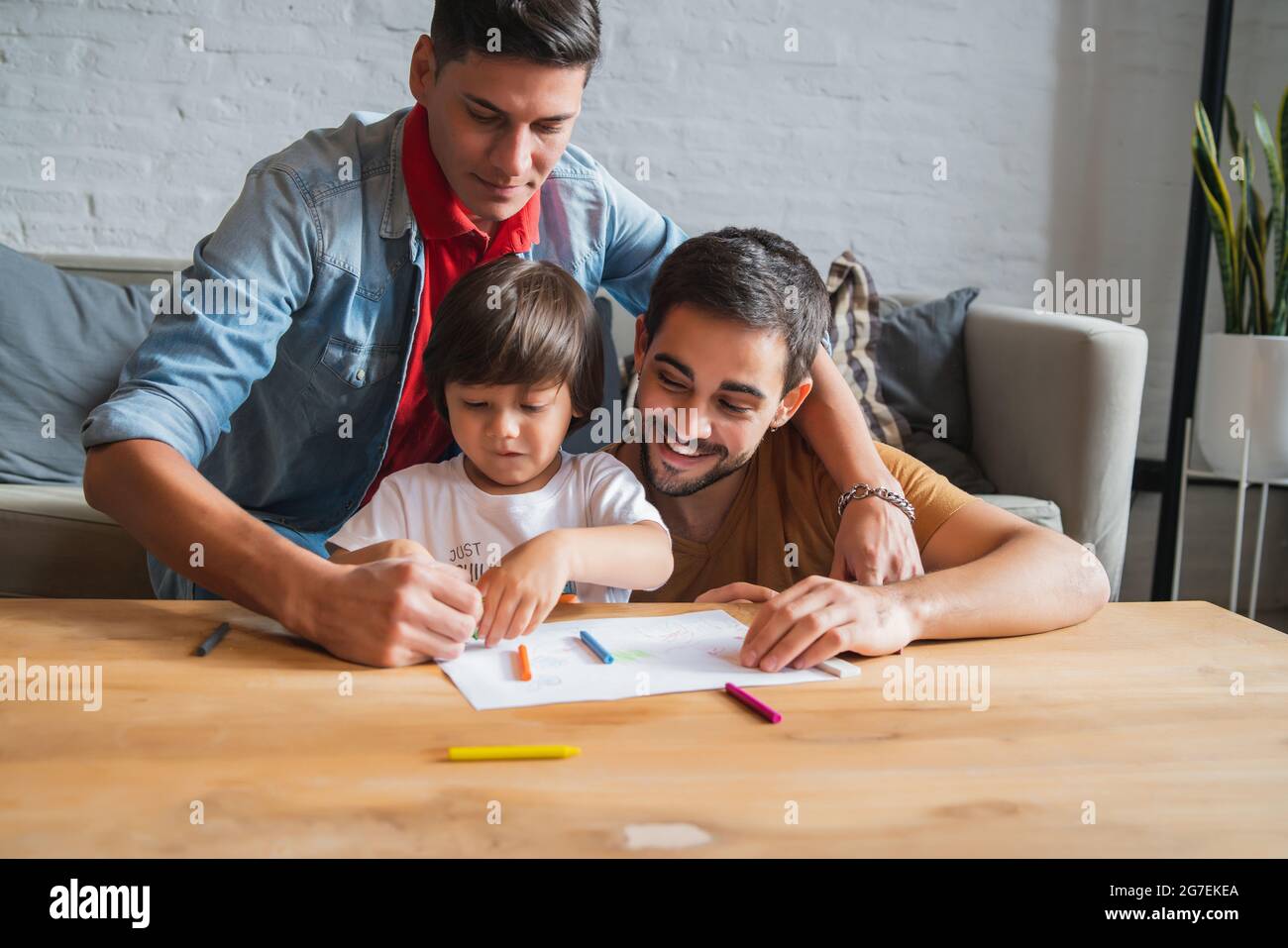 Couple gay et leur fils s'amusant ensemble tout en dessinant à la maison. Banque D'Images
