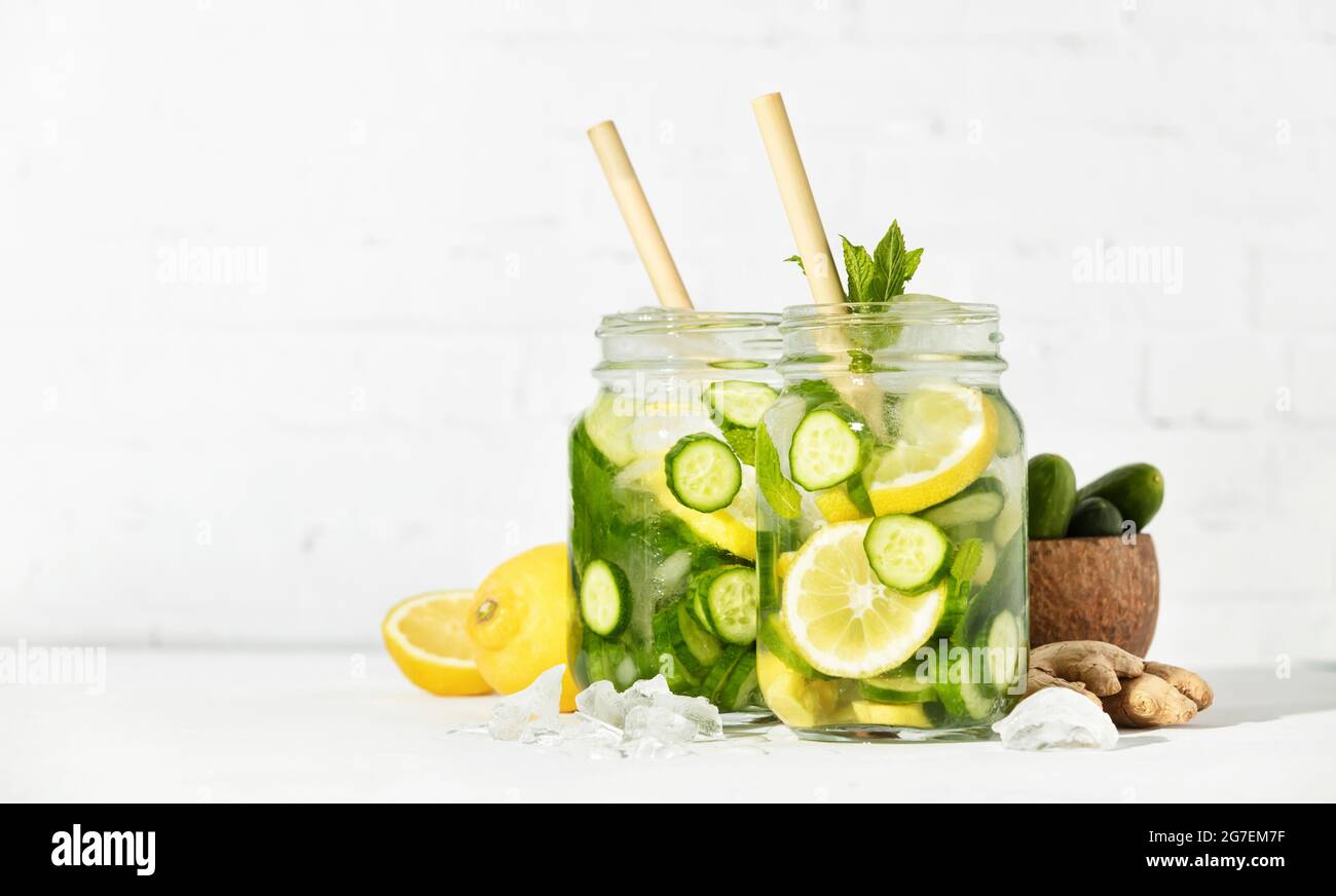 Détox d'été et boissons rafraîchissantes avec concombre, citron, menthe et gingembre sur fond de mur de briques blanches. Ombres ensoleillées Banque D'Images