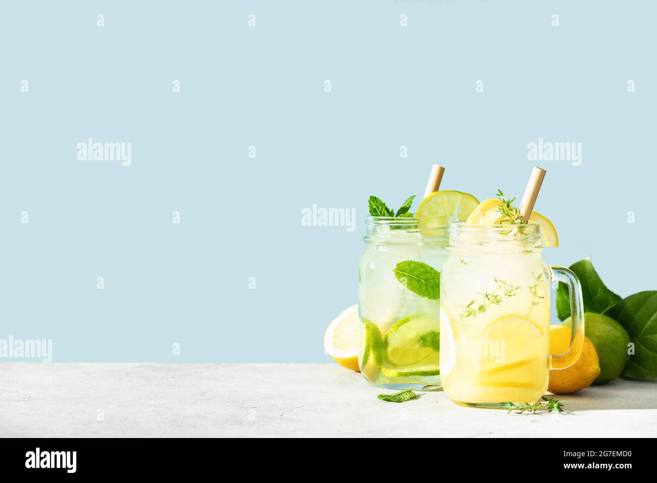 Limonade et mojito sur fond bleu ciel. Cocktails maison rafraîchissants, boissons estivales, sélection. Ombres ensoleillées Banque D'Images