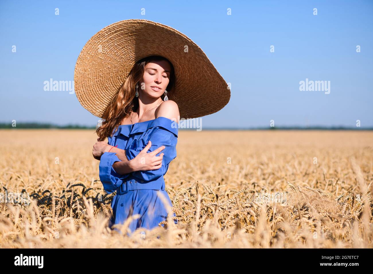 Adorable jeune fille dans un chapeau à large bord dans un champ de blé. Une  femme se chopine elle-même Photo Stock - Alamy