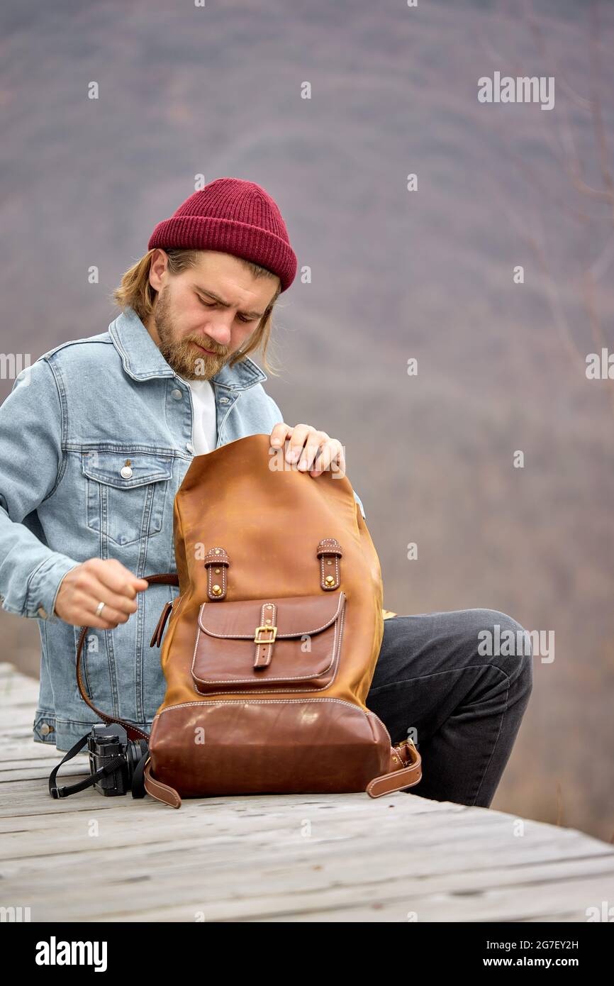 touriste homme touriste homme ouverture cuir brun sac à dos pendant la  randonnée dans les montagnes, assis ayant le repos, seul, vue latérale  portrait de beau type de hipster dedans Photo Stock -