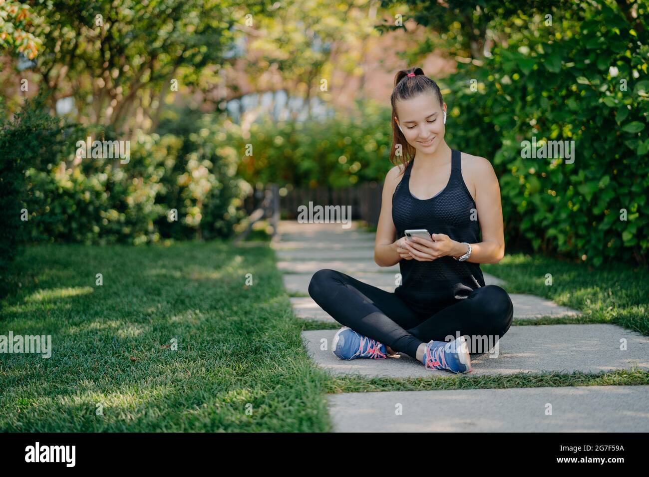 La femme sportive a une pause pour des contrôles de rafraîchissement messages et de notification partage le contenu sur la forme physique extérieur habillée en vêtements actifs mène en bonne santé Banque D'Images