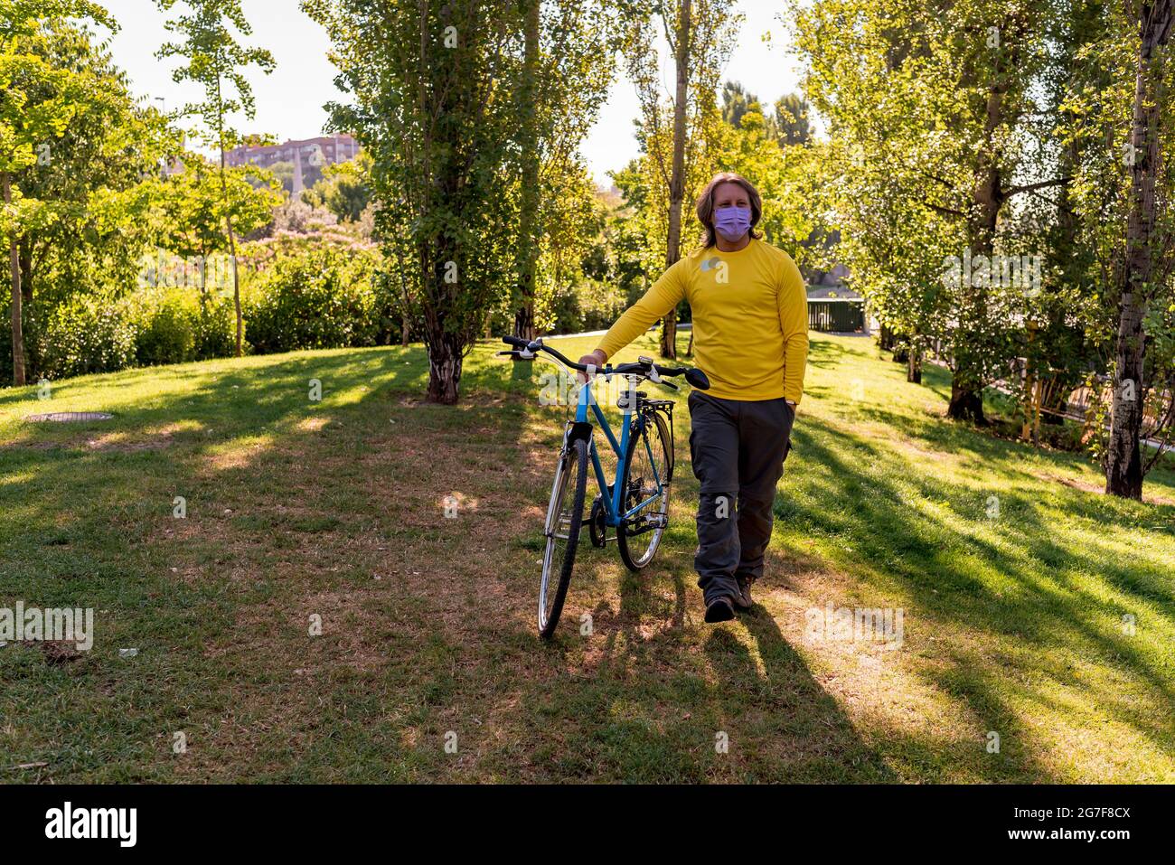 Homme marchant dans le parc avec son vélo Banque D'Images