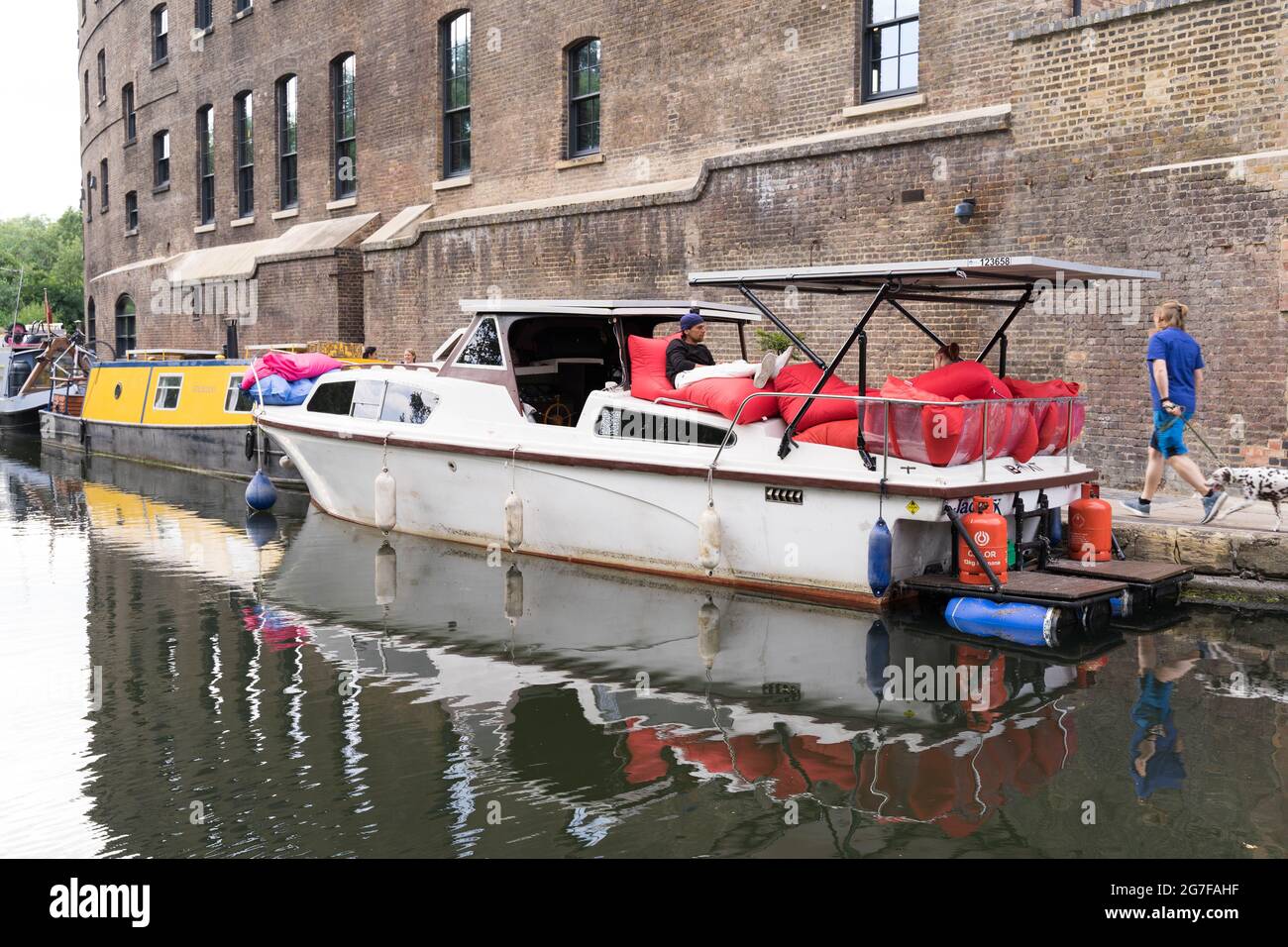 Homme reposant dans un bateau alimenté par un panneau solaire dans le canal de Regent, Londres Angleterre Royaume-Uni Banque D'Images