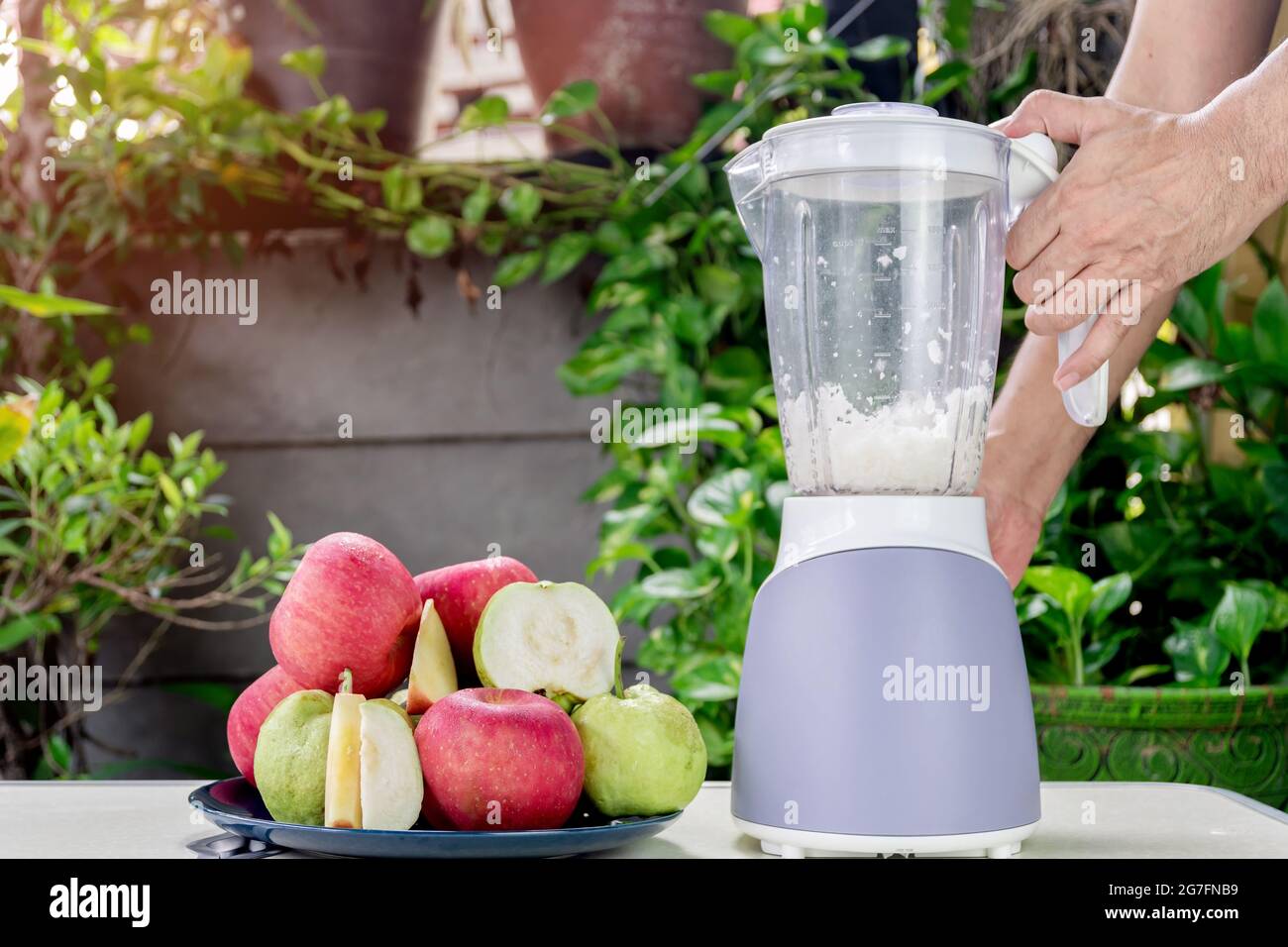 Main des gens utilisent un mélangeur électrique pour faire de la pomme  fraîche et du jus de goyave Photo Stock - Alamy