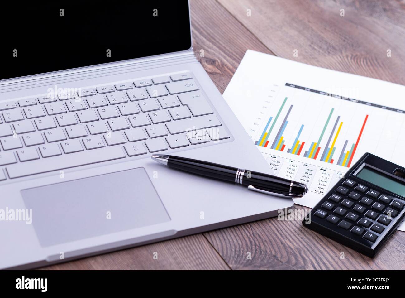 La photo montre un poste de travail avec ordinateur, calculatrice et stylo sur une table de travail en bois Banque D'Images