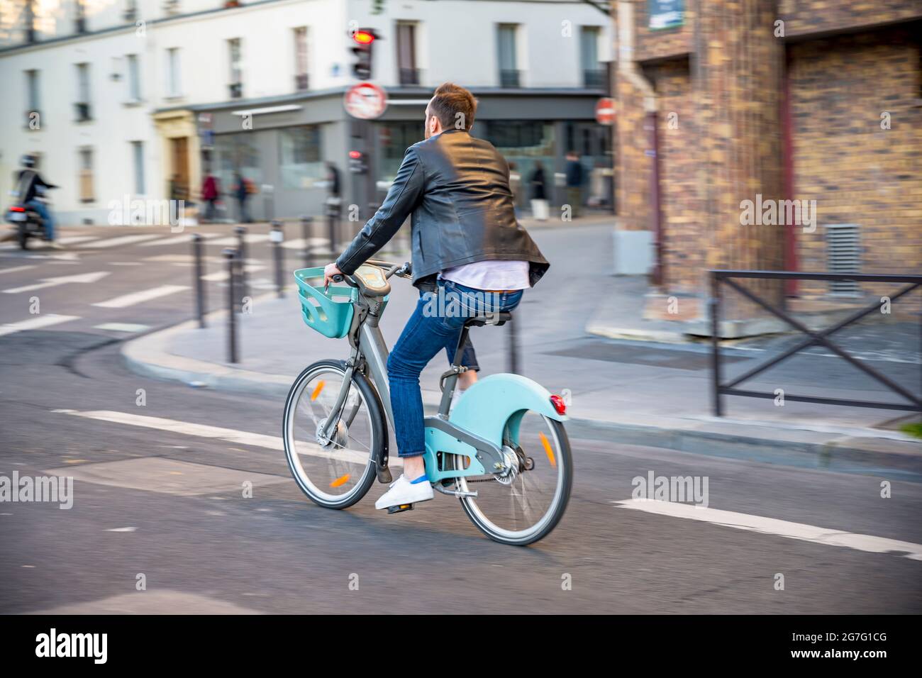 Un homme n un vélo loué avec un moteur électrique pour les voyages en ville se déplace dans une rue dans le vieux Paris préférant un style de vie sain en utilisant le vélo et cycl Banque D'Images