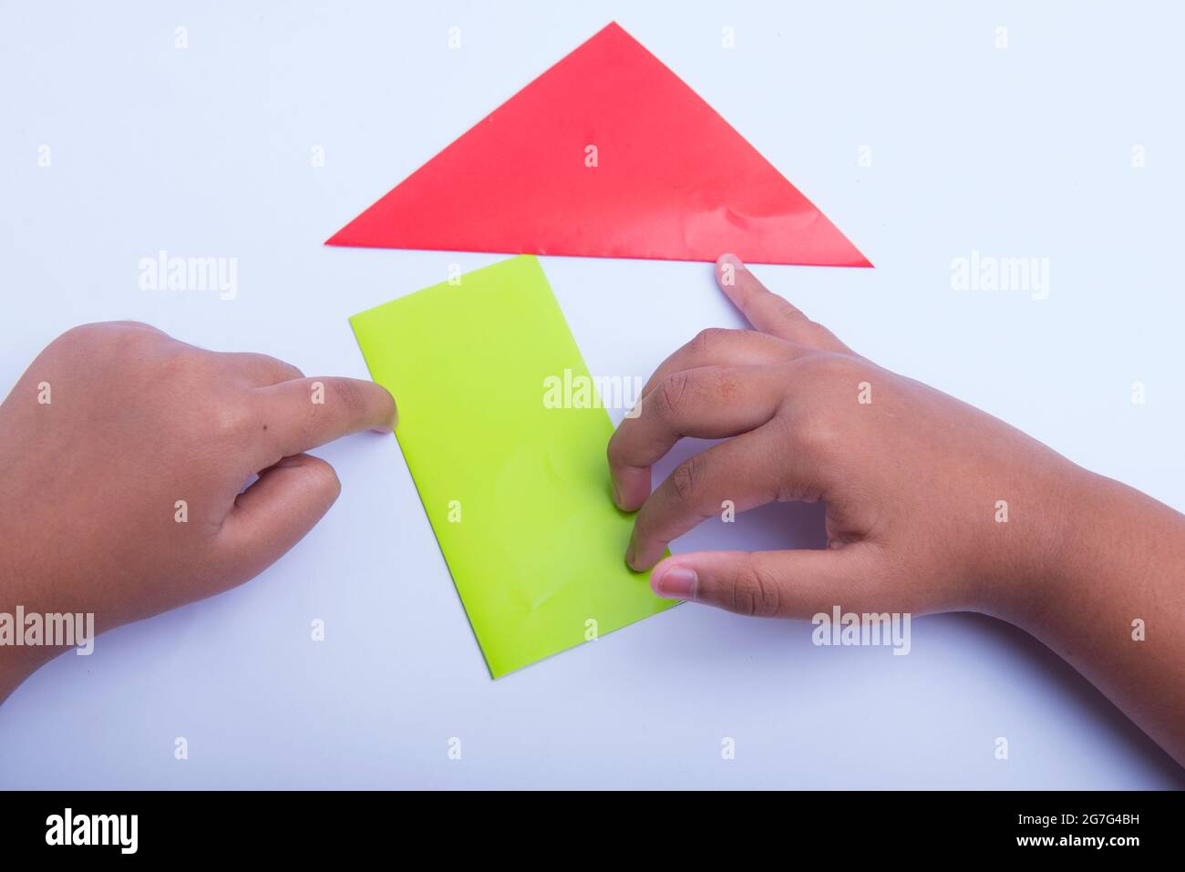 Pliage manuel d'un papier de couleur isolé sur fond blanc Banque D'Images