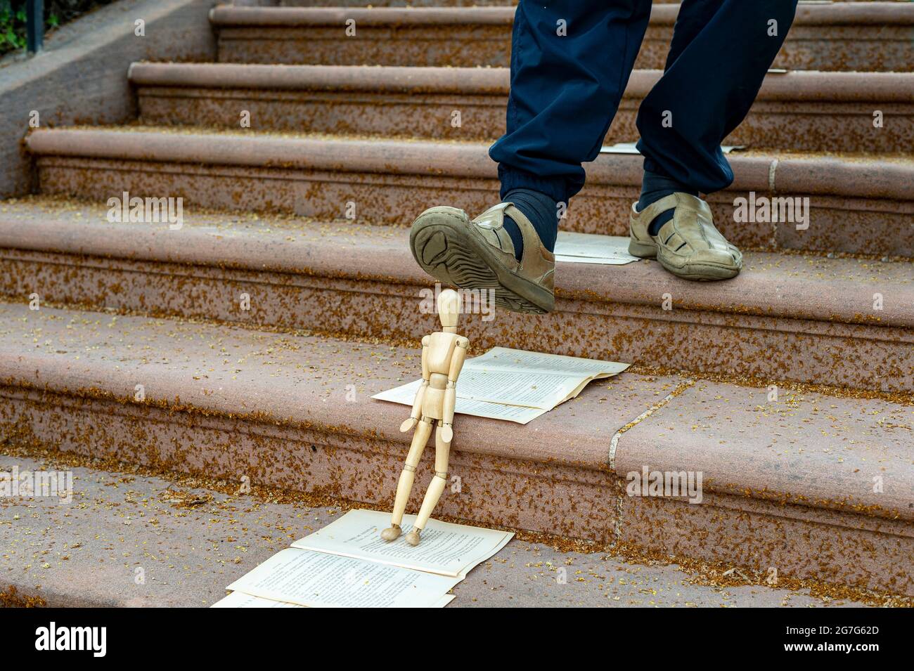 Marionnette écrasée par un pied à Haguenau, Alsace, France. La marionnette penchée contre un escalier est sous le pied d'une personne qui descend. Banque D'Images