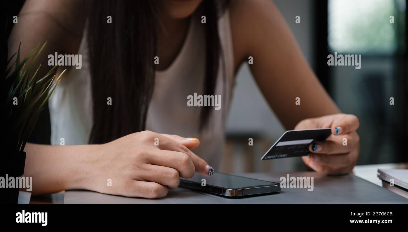 Femme aime avec l'application d'achat en ligne et regardant la carte de crédit pour remplir le numéro de paiement. Banque D'Images