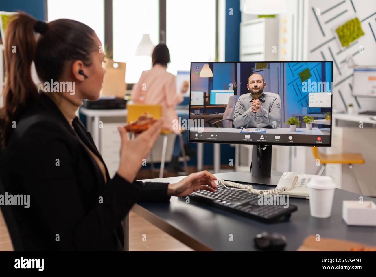 Femme d'affaires ayant livraison repas à emporter pendant le déjeuner à emporter à la réception pendant la conférence de réunion vidéo en ligne avec le directeur à distance. Entrepreneur mangeant de la pizza sur le lieu de travail Banque D'Images