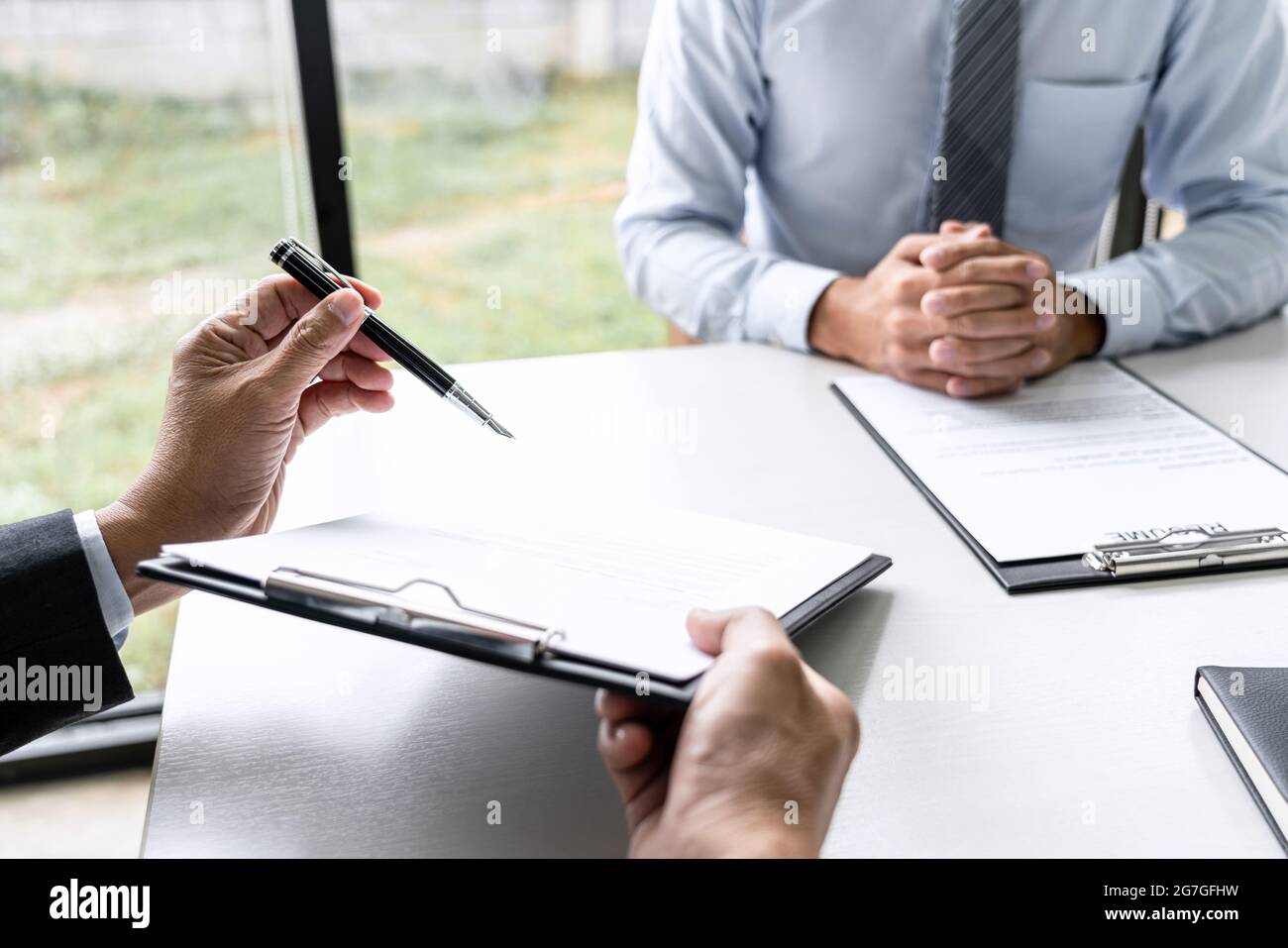 Gestionnaire principal du comité lisant un curriculum vitae au cours d'une entrevue d'emploi, l'employeur interviewant pour demander à un jeune homme candidat à un emploi de parler au bureau Banque D'Images