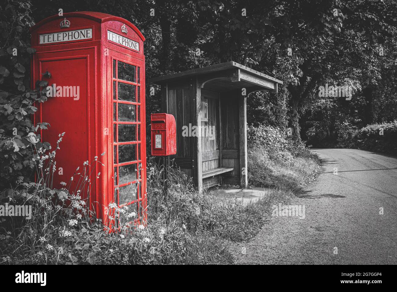 Cabine téléphonique traditionnelle britannique rouge, boîte postale et arrêt de bus en bois, couleur sélective sur fond noir et blanc, pas de personne. Pays de Galles, Royaume-Uni Banque D'Images