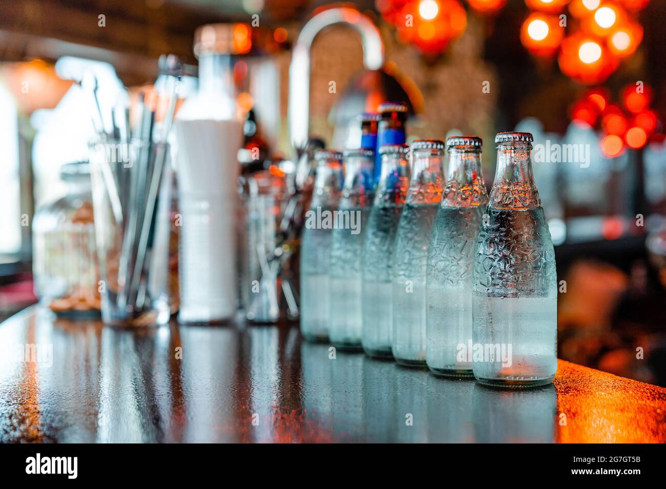 Bouteilles en verre avec eau froide rafraîchissante placées en rangée sur  un comptoir en bois dans le bar Photo Stock - Alamy