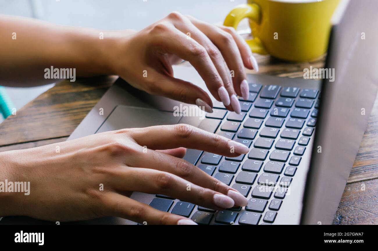 Une femme indépendante non reconnaissable a été coupée en tapant sur le clavier d'un ordinateur portable tout en travaillant sur un projet à distance sur la terrasse d'un café Banque D'Images