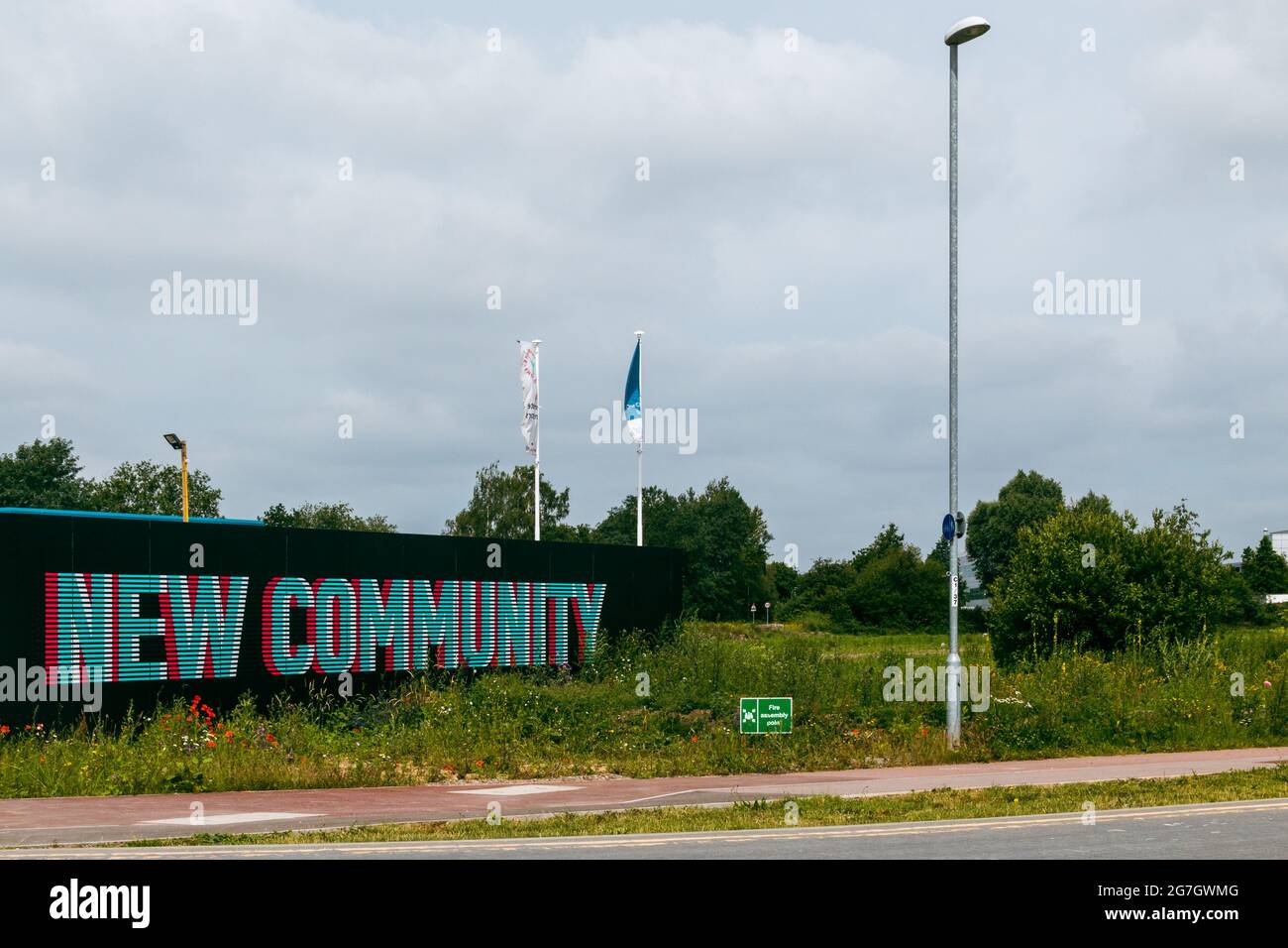 Les mots Nouvelle Communauté ont été peints sur une clôture noire à côté d'un champ vide. Cambridge, Royaume-Uni. Banque D'Images