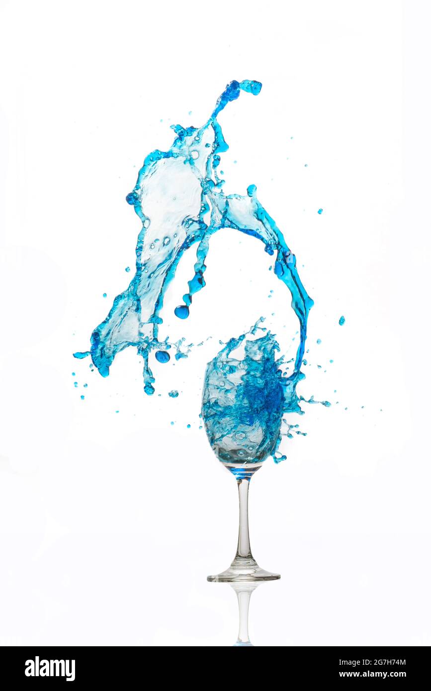 Verre à vin sur fond blanc avec une éclaboussure d'eau bleue. Banque D'Images