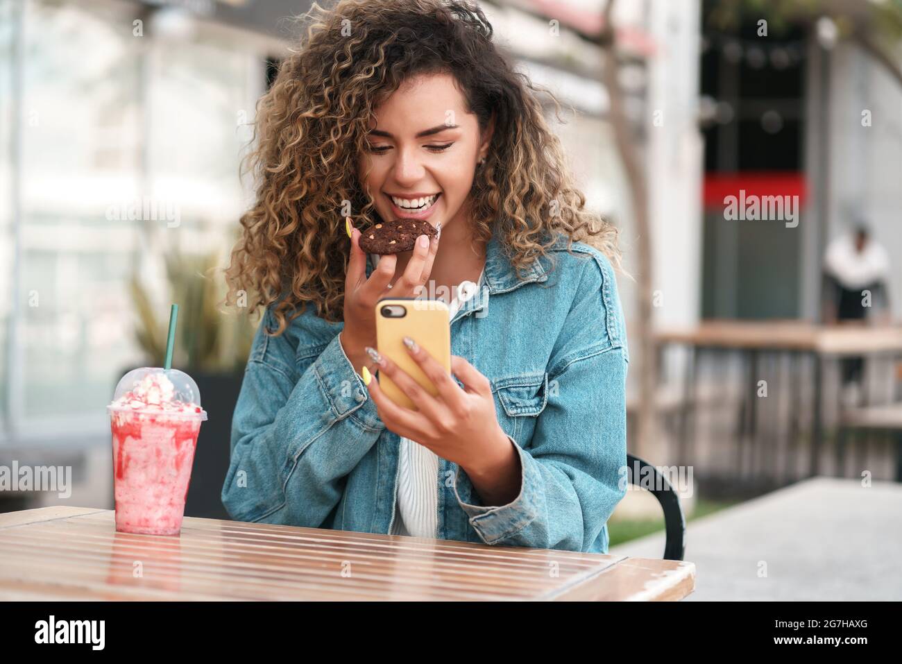 Femme latine utilisant un téléphone portable tout en étant assise dans un café. Banque D'Images