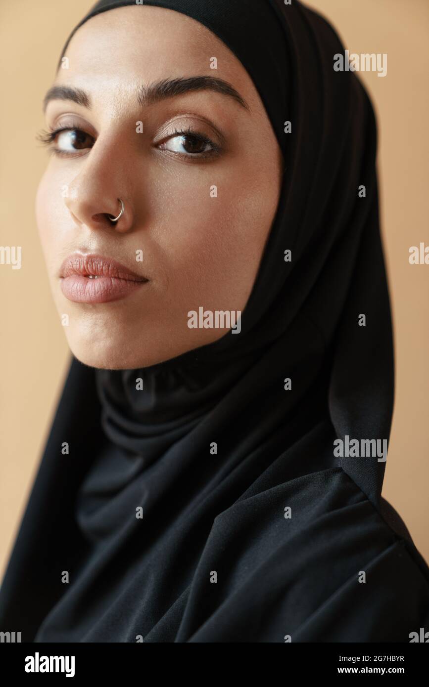 Un portrait de la femme musulmane concentrée avec le nez percé dans le hijab  debout dans le studio orange Photo Stock - Alamy