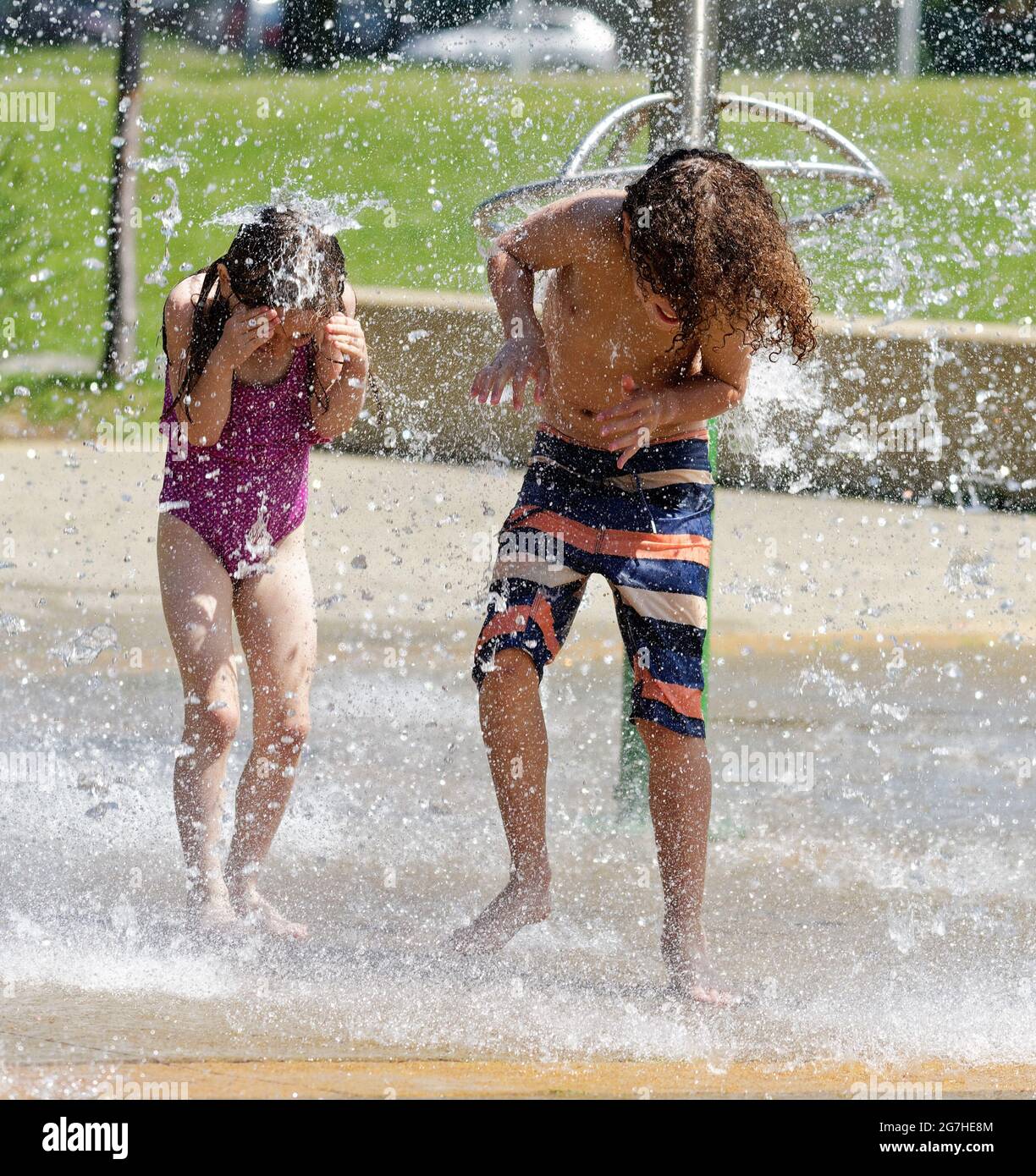 Un garçon et une fille (7 et 9 ans) jouant dans des jeux aquatiques et des fontaines à Québec, Canada Banque D'Images