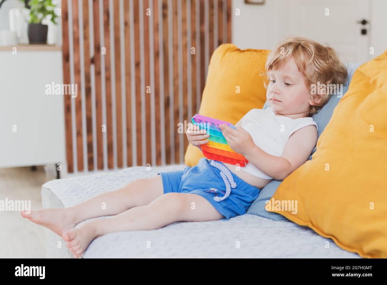 Petit garçon tenant anti stress sensoriel pop il jouets dans sa main jeune tout-petit se plaquant avec le jouet sensoriel de violon Banque D'Images