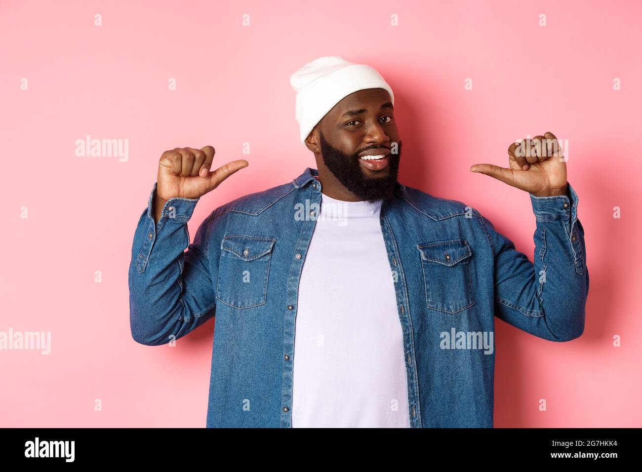 Homme à barbe noire confiante en bonnet hipster et chemise en denim, se  montrant avec un visage assuré, debout sur fond rose Photo Stock - Alamy